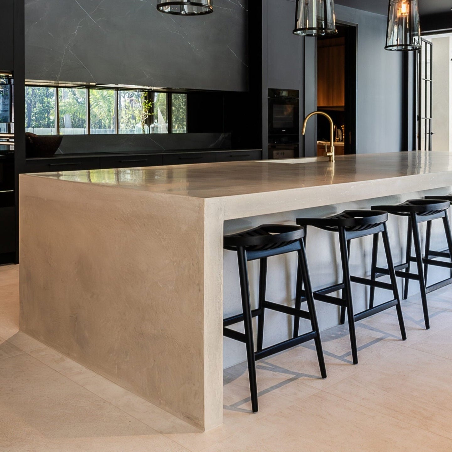 Modern kitchen with a island and stools, featuring black pendant lights and a sleek design.